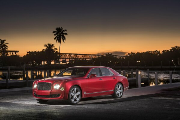 Elegante Bentley di colore rosso su uno sfondo di palme