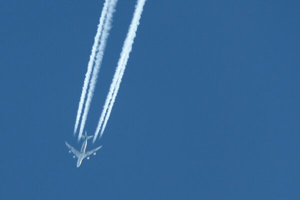 L aereo vola nel cielo blu lasciando una scia bianca