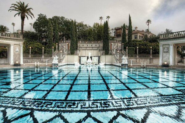 Piscina blu al Parco del resort con scale e cipressi