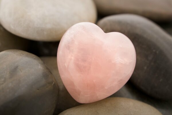 Cuore di pietra di colore rosa tra le pietre comuni