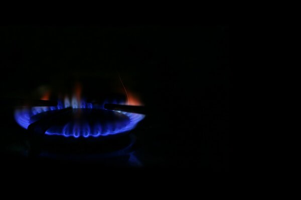 Bruciatore a gas su sfondo nero. Fiamme blu e rosse