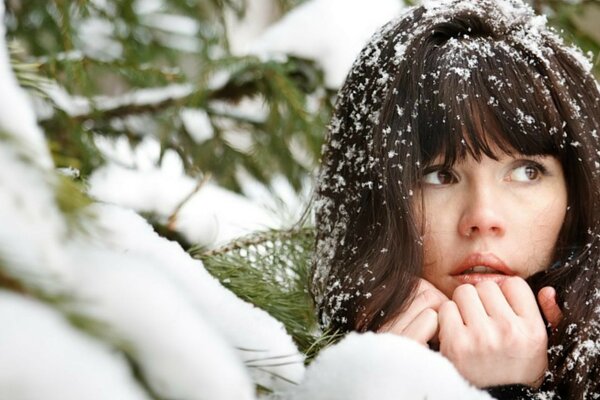 Ragazza con capelli nevicati tra la foresta invernale