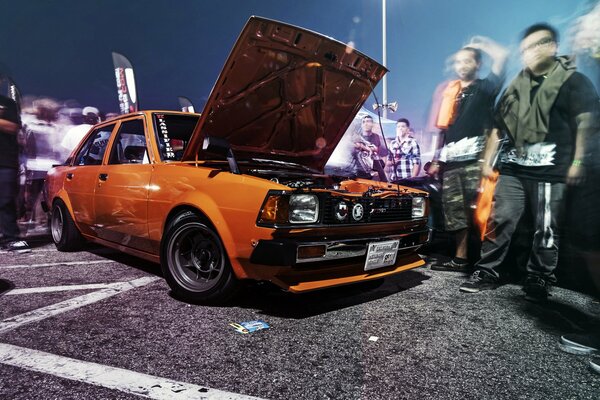 Toyota Corolla arancione. Persone in movimento
