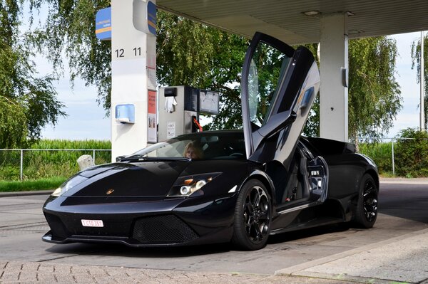 Porta aperta di un auto sportiva nera alla stazione di servizio