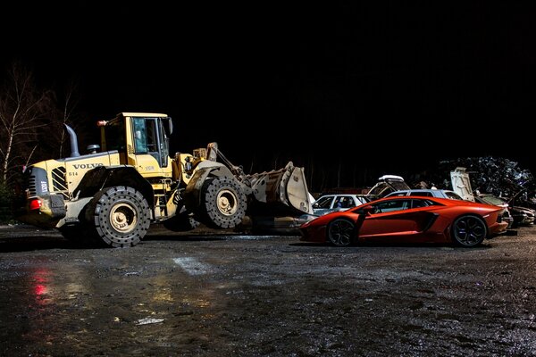 Bulldozer Volvo di notte con Lamborghini arancione