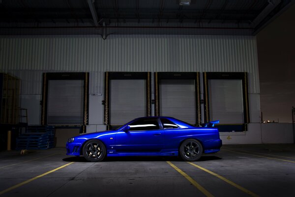 L auto Nissan R34 di colore blu si trova al buio sulla strada
