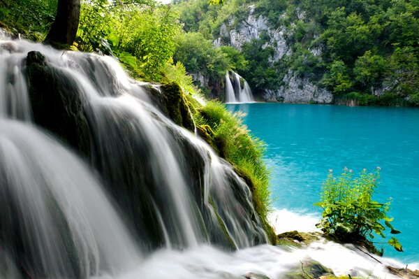 Cascata di montagna che sfocia nel lago blu