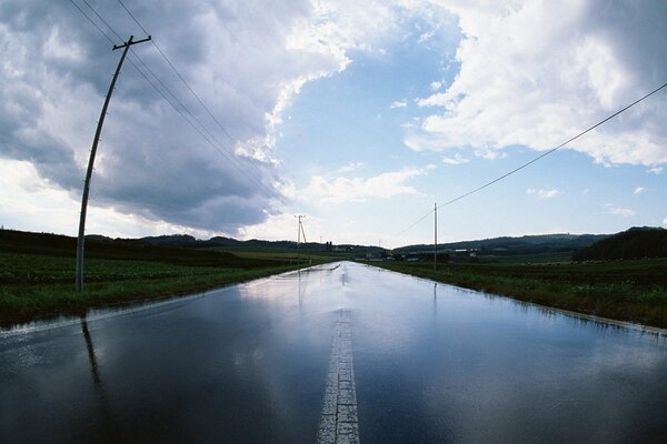 Una strada che si estende verso l orizzonte, con pilastri lungo i bordi delle strade e un cielo con grandi nuvole
