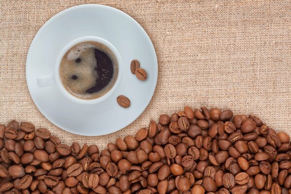 Tazza di caffè su piattino e chicchi di caffè