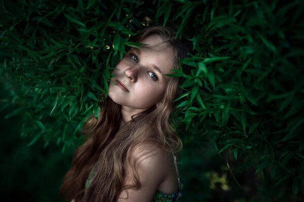 Ragazza dai capelli lunghi con le lentiggini in mezzo al verde