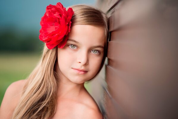 Bella ragazza bionda con rosa nei capelli