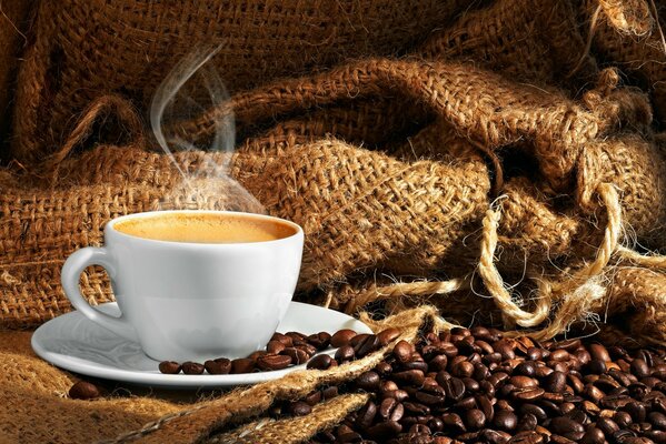 Caffè fumante in tazze e chicchi di caffè