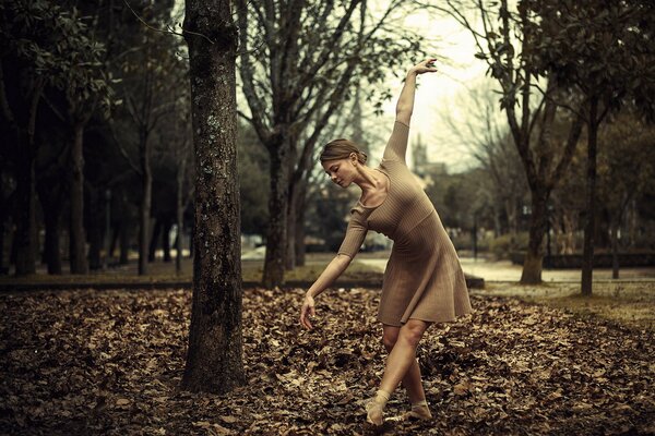 Ragazza che balla sul fogliame autunnale