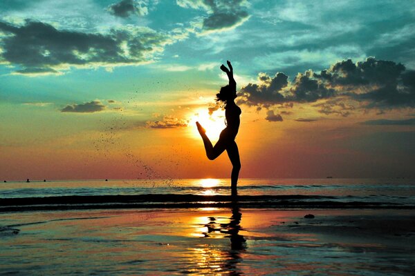 Sulla spiaggia, una ragazza gioiosa corre in silhouette