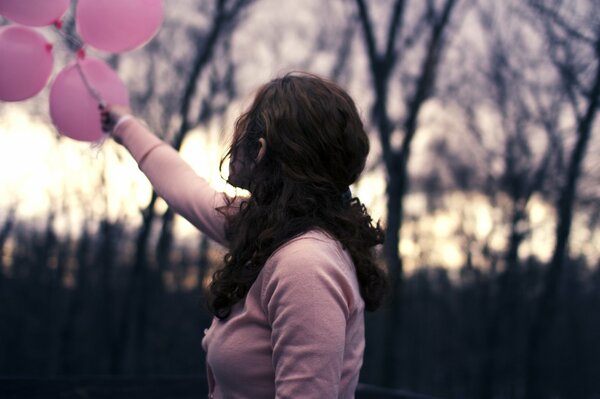 Ragazza in possesso di palloncini di colore rosa dietro di lei sono sfondo sfocato