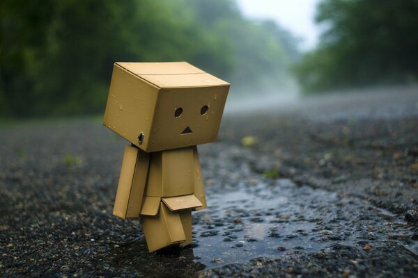 Scatola a forma di robot triste sull asfalto