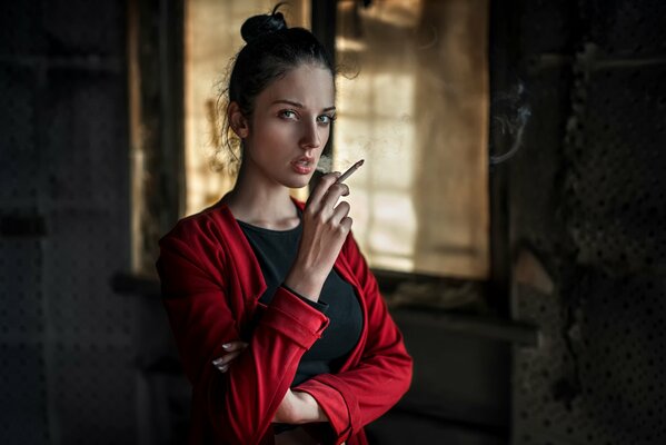 Ragazza in rosso con una sigaretta sulle mani