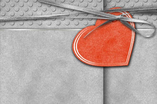 Cartolina grigia legata con un nastro con un cuore rosso