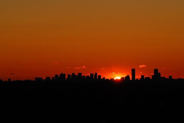 Sagoma di una grande città sullo sfondo di un tramonto rosso