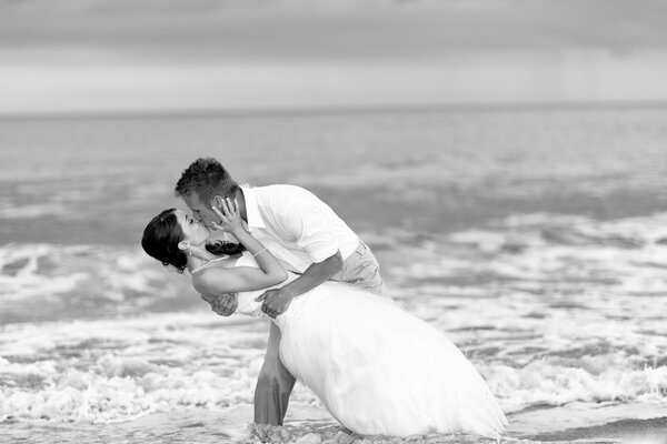 Un uomo e una donna al matrimonio si baciano sulla riva
