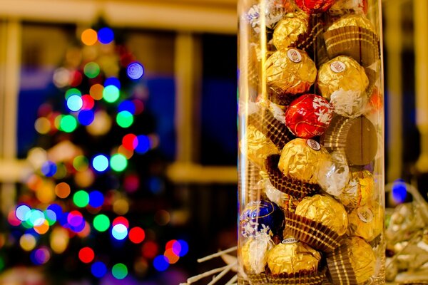 Barattolo di caramelle in primo piano e albero di Natale decorato sul retro