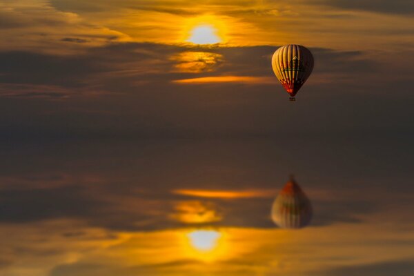 Riflesso nell acqua di un pallone che vola al tramonto