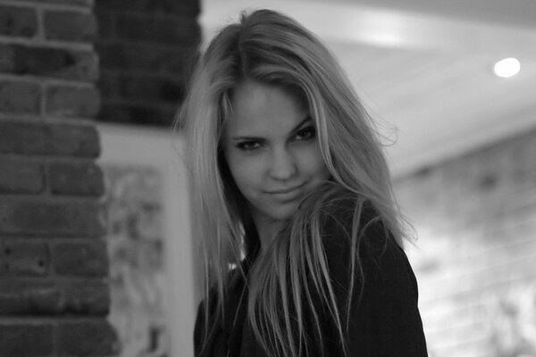 Foto in bianco e nero della modella Emily Marie. Nella foto, la ragazza ha strizzato gli occhi in modo carino