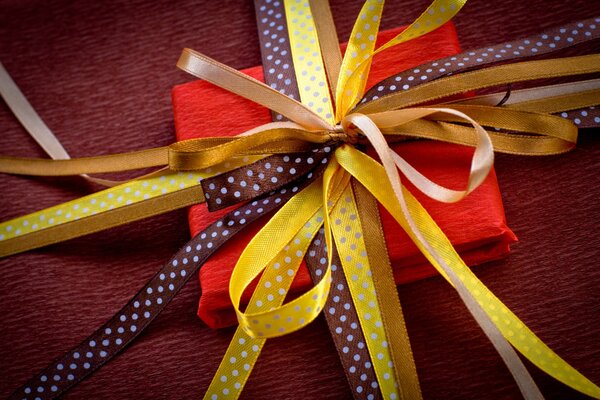 Scatola regalo quadrata rossa legata con nastri gialli