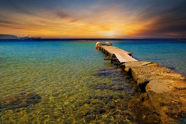 Ponte che va in mare sullo sfondo del tramonto